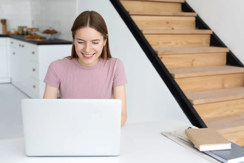 A woman at home working on a laptop representing flexible online coaching