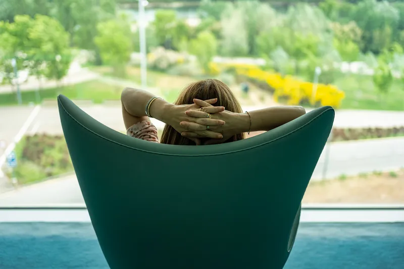 Woman sitting quietly in a chair looking out at nature, representing ADHD, hormonal changes, emotional overwhelm, burnout, and nervous system exhaustion in women.