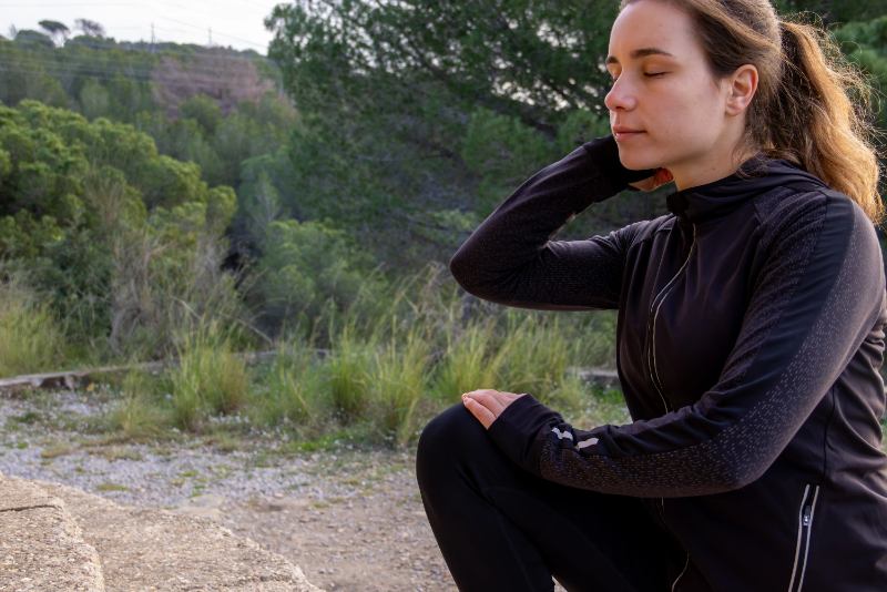 Woman sitting outdoors in nature reflecting on ADHD overwhelm and mental fatigue often mistaken for laziness