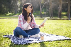 Woman sitting outdoors using a tablet in a calm park setting