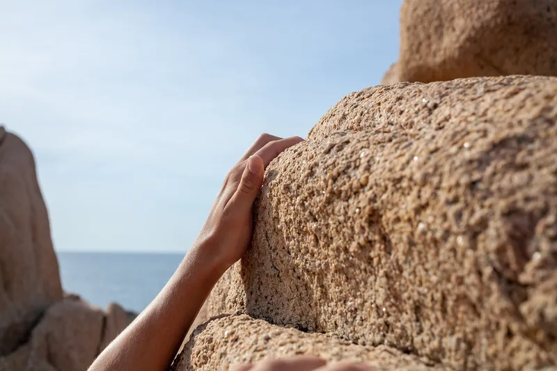 A close-up of someone climbing over rocks, representing how difficult it can be to recognise your own progress and growth.