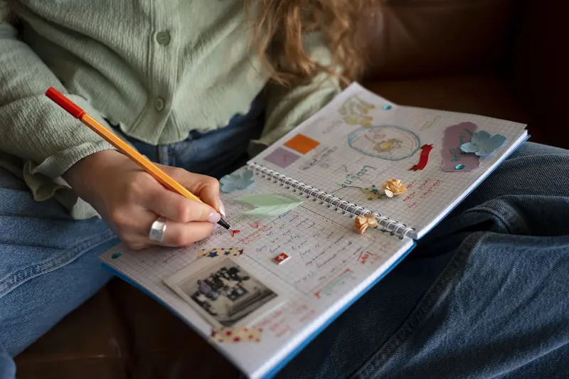 Woman using a journal and visual planning tools to support ADHD organisation, focus, emotional regulation, and overwhelm reduction.