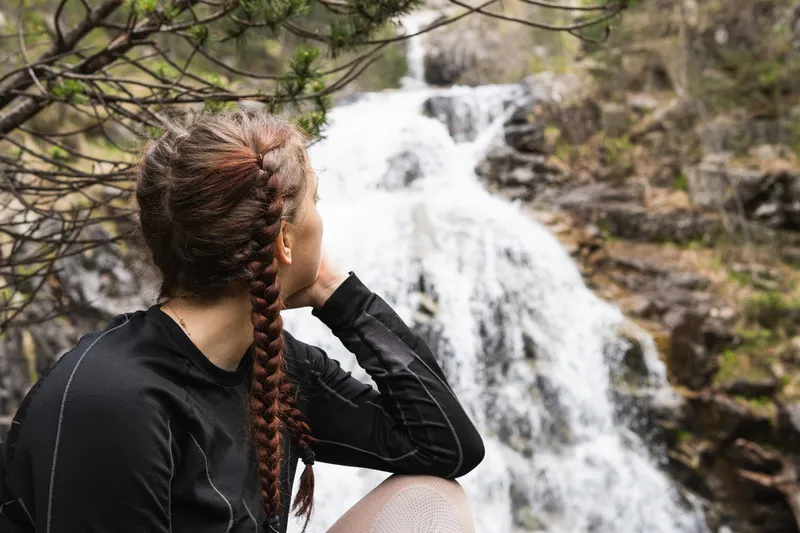 Woman looking at a waterfall in nature, representing overwhelm, mental exhaustion, and the hidden challenges of simple everyday tasks with ADHD.