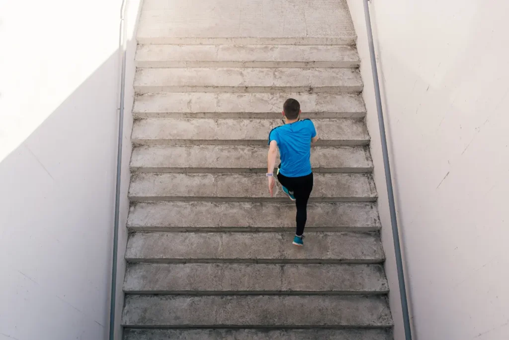 Man with a blue top running up stairs chasing his ADHD coaching goals.