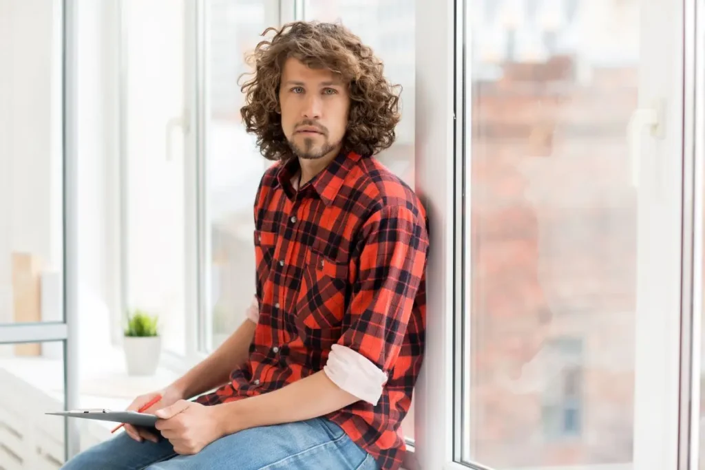 Man sitting by office window during ADHD coaching session, reflecting on focus, clarity, and personal growth