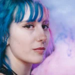 Young woman with blue hair looking thoughtful, representing creativity, individuality, and self-acceptance through ADHD coaching.