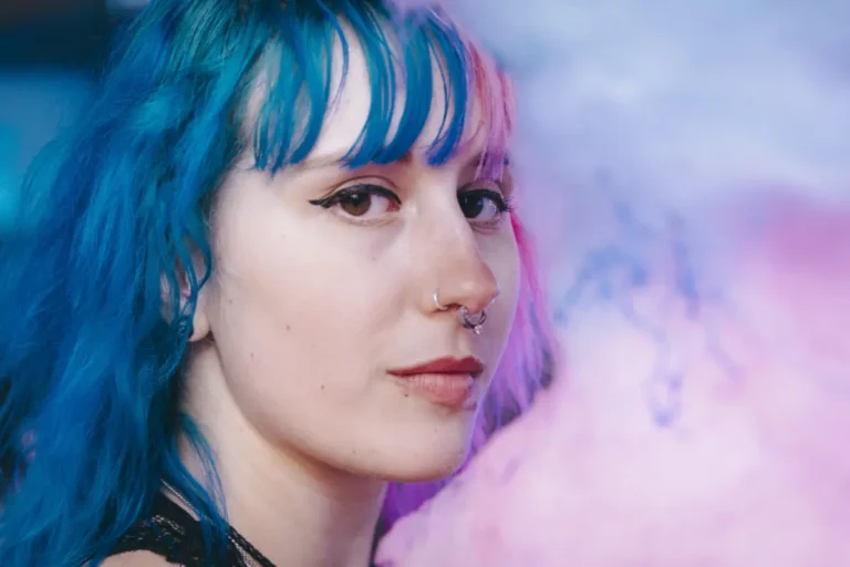 Young woman with blue hair looking thoughtful, representing creativity, individuality, and self-acceptance through ADHD coaching.