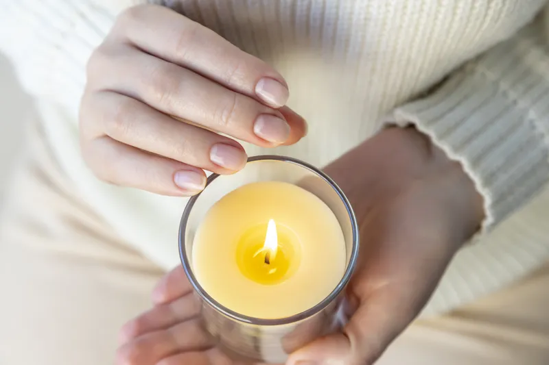 A close-up of someone holding a lit candle, representing the self-reflection and self-compassion involved in understanding why ADHD is not laziness.
