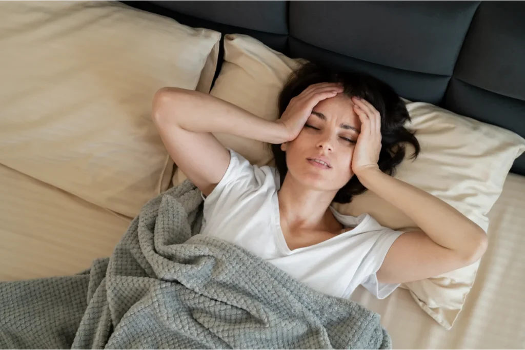 Woman lying awake in bed in the early morning, feeling exhausted after poor sleep with ADHD