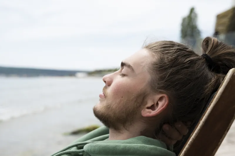 A person sitting quietly by the water, representing the experience of ADHD emotional overwhelm and taking a moment to process strong emotions.