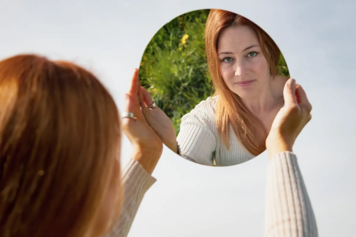 Woman looking at her reflection in the mirror representing self-awareness