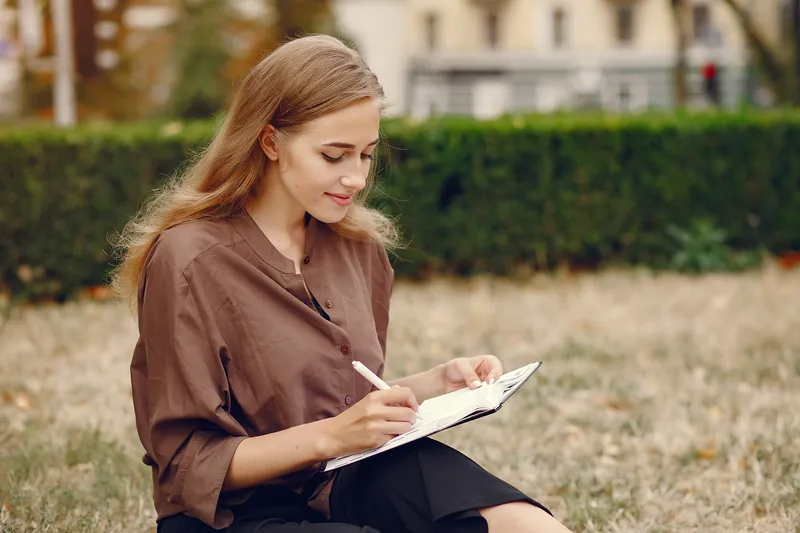 Woman journalling outdoors during ADHD coaching self-reflection practice