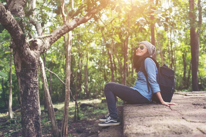 Woman sitting quietly in woodland reflecting on emotions and ADHD patterns during therapy support