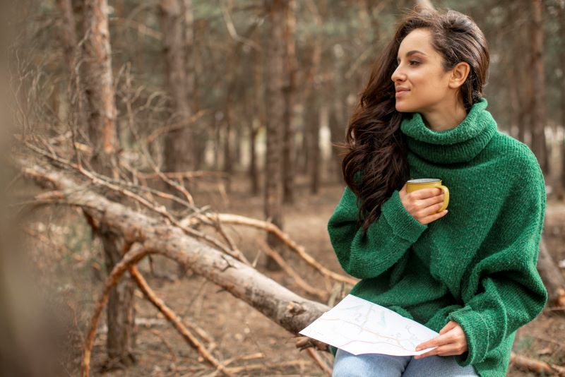 A calm outdoor scene showing a woman sitting in nature, reflecting and journalling, representing clarity, self-understanding, and thoughtful ADHD support.