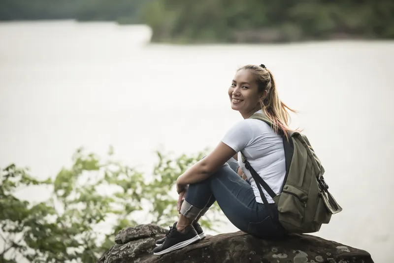 Woman sitting beside water in a calm reflective outdoor setting