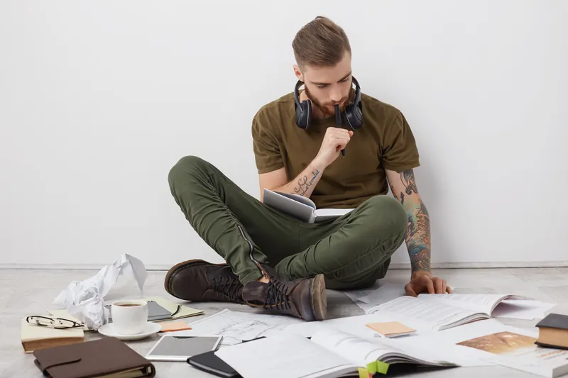 Man sitting with notebooks and papers while trying to make decisions with ADHD.