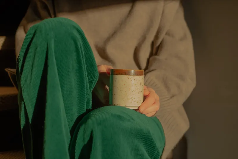 A close-up of someone sitting with a warm drink after work, reflecting the mental and emotional exhaustion that can come with ADHD.