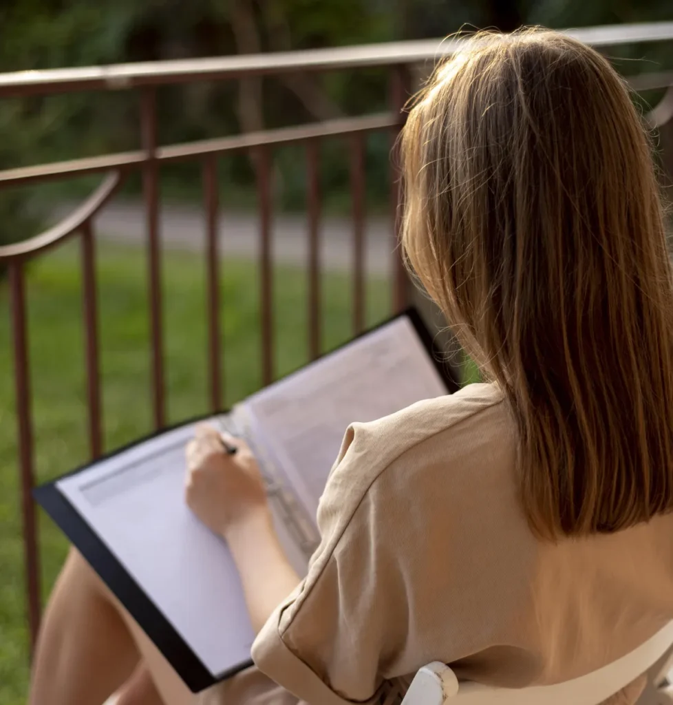 Woman writing outdoors while reflecting during ADHD coaching and Counselling at work.