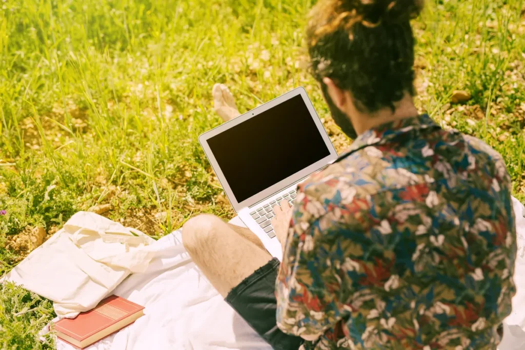 Person using a laptop outdoors in a natural setting, representing confidence, self-awareness and positive change.