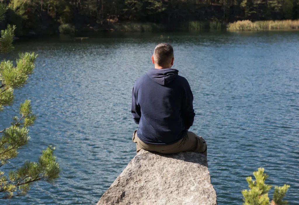 Man sitting by a lake reflecting on feeling lazy with ADHD.