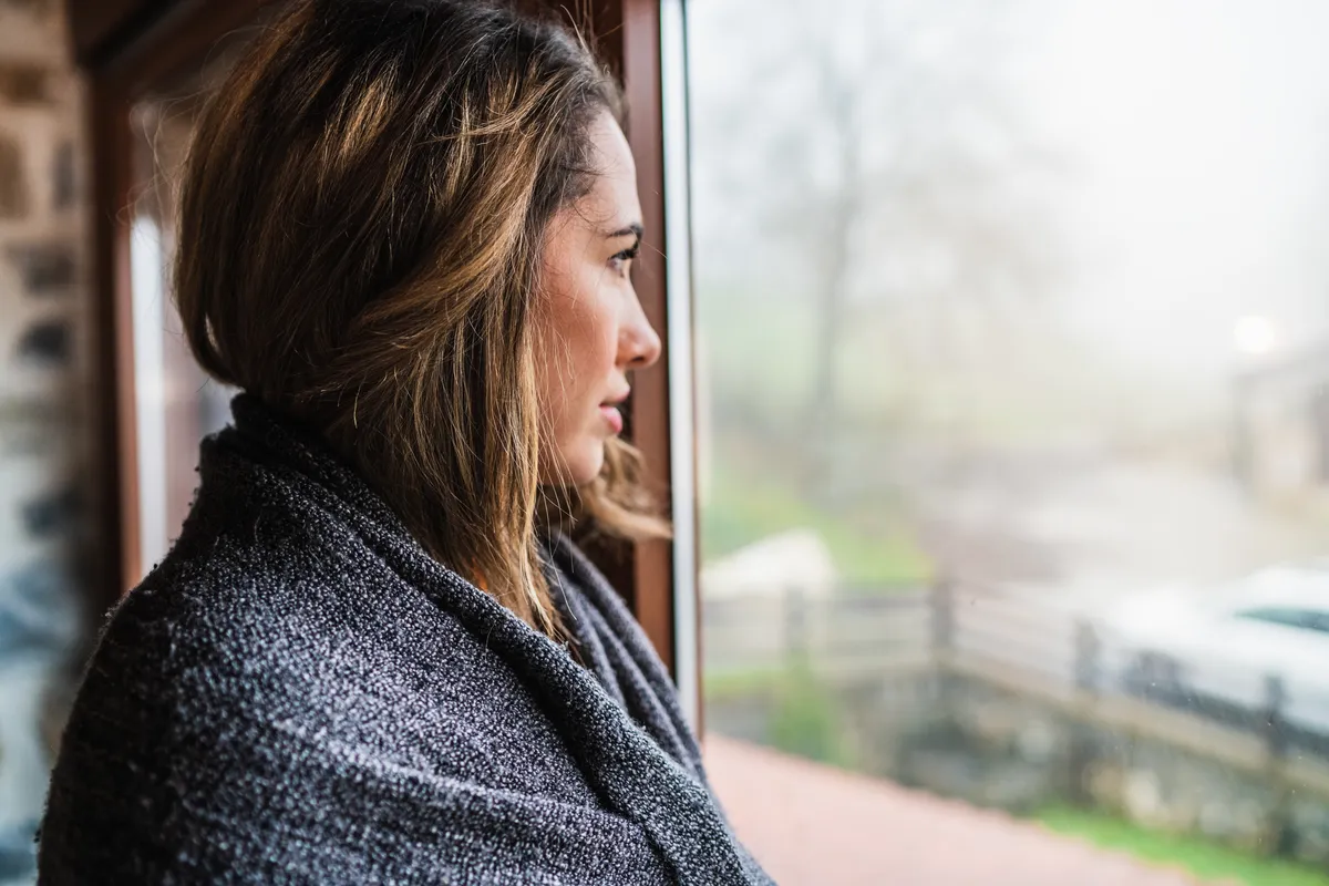 Woman looking out of a window reflecting on ADHD emotional overwhelm.