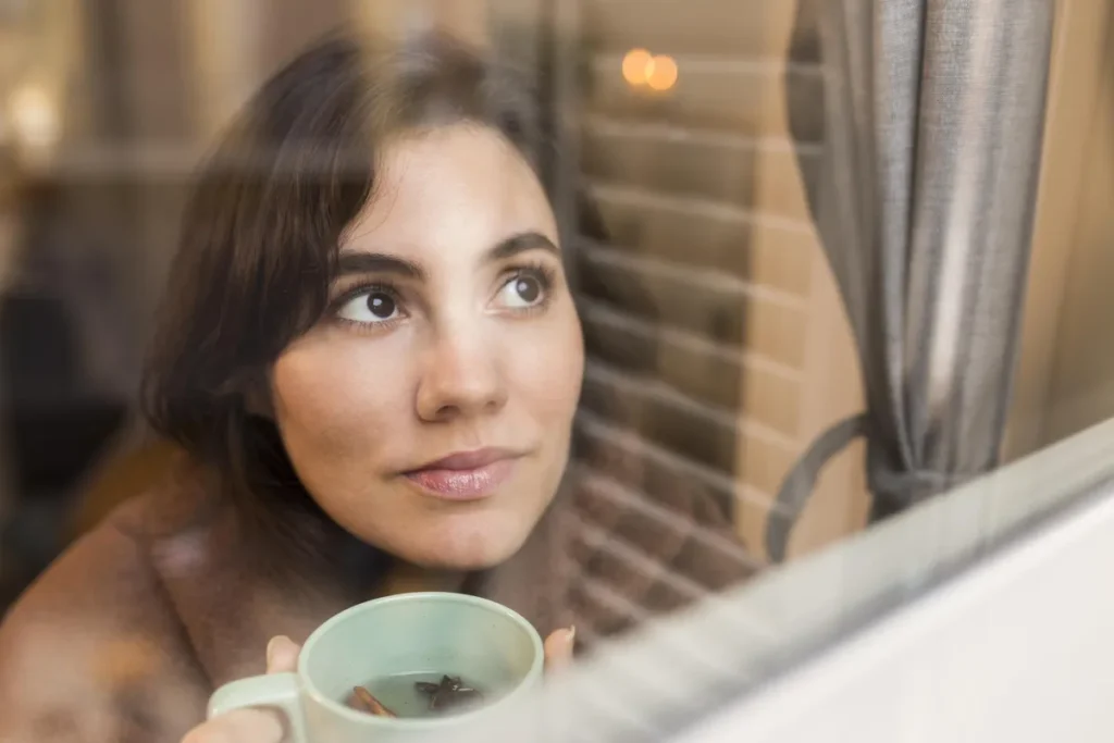 Woman looking out of a window reflecting on self-compassion with ADHD.