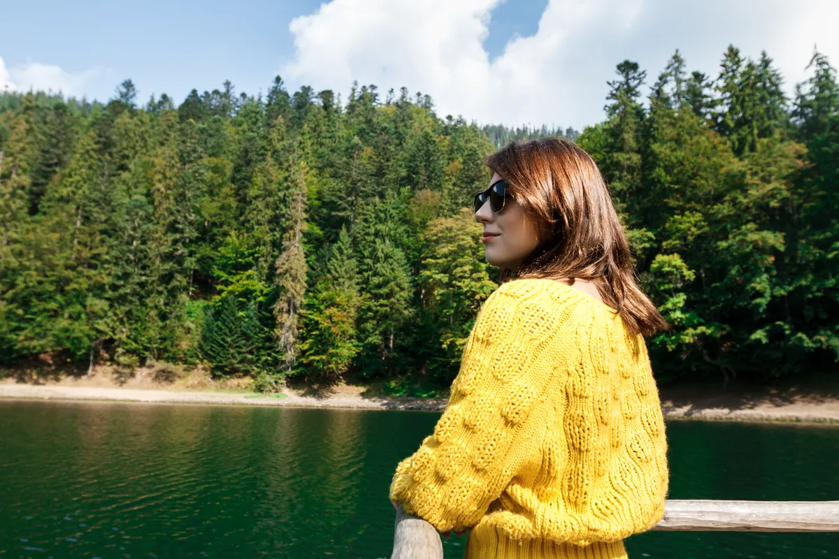 Woman looking across a lake reflecting on ADHD and hormones.