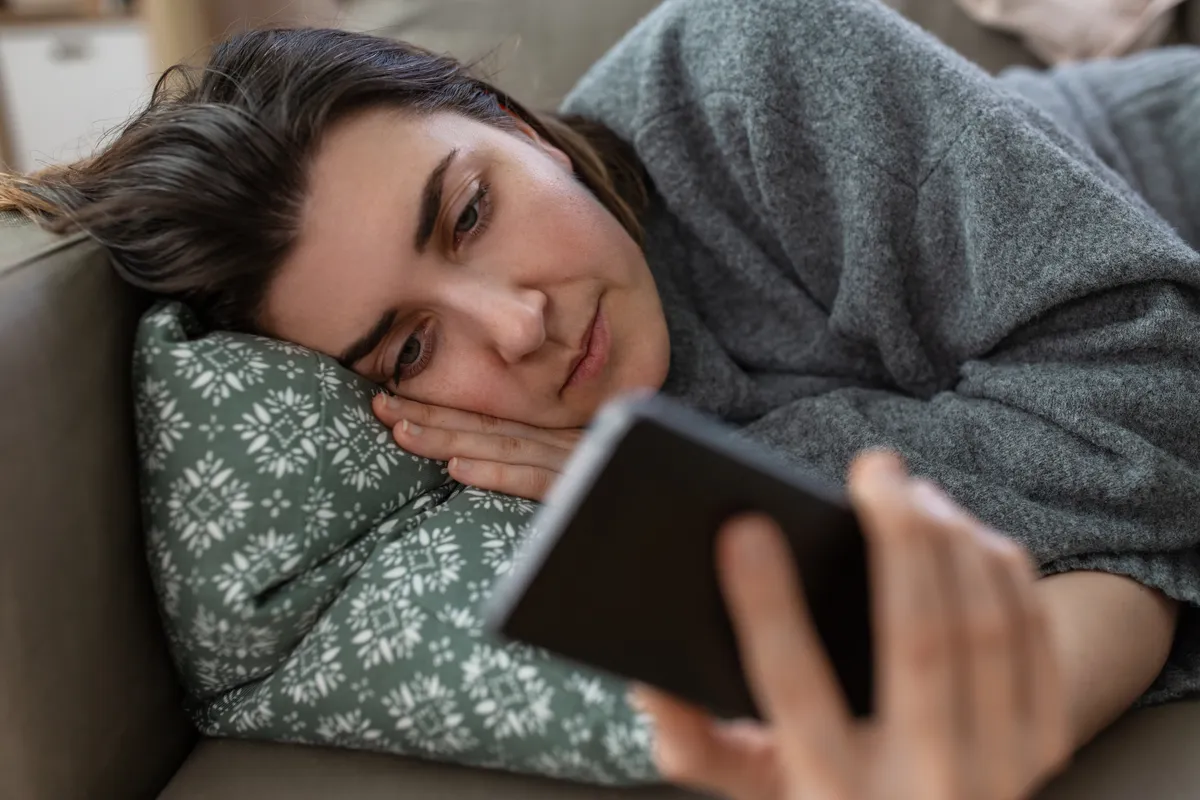 Woman lying on a sofa finding it hard to get things done with ADHD.