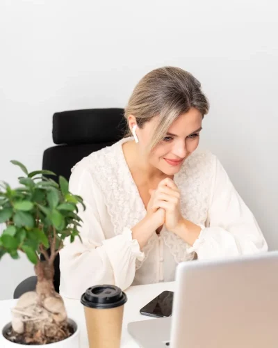 Virtual ADHD coaching for women – supportive one-to-one session Smiling woman in an online ADHD coaching session, seated at desk with coffee and plant